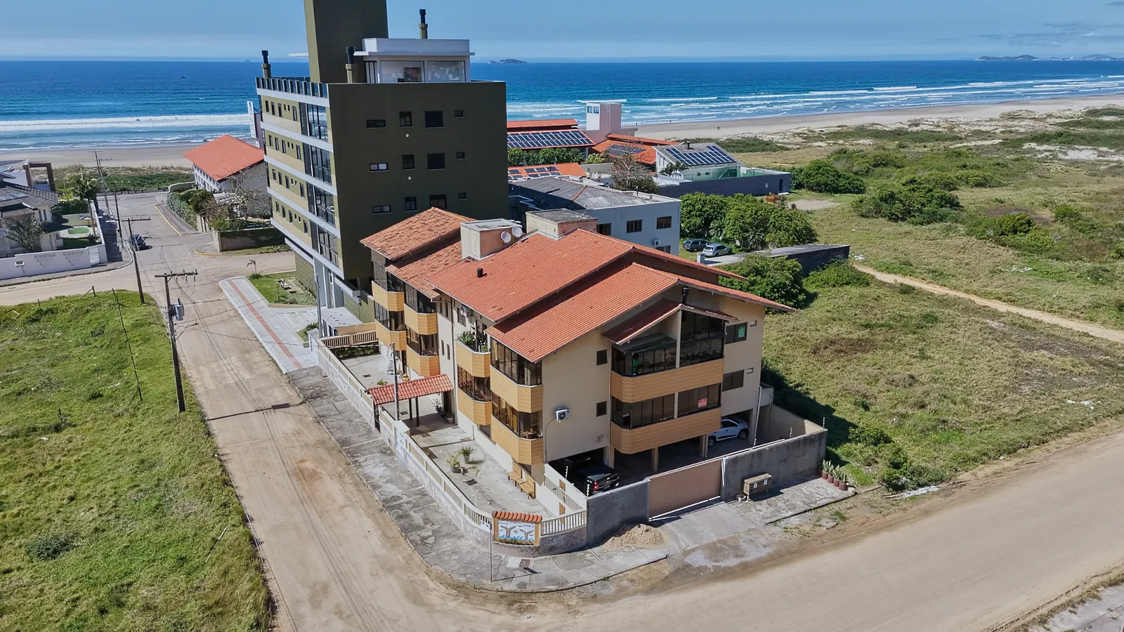 Vídeo aéreo do prédio e do entorno, com a praia ao fundo.
