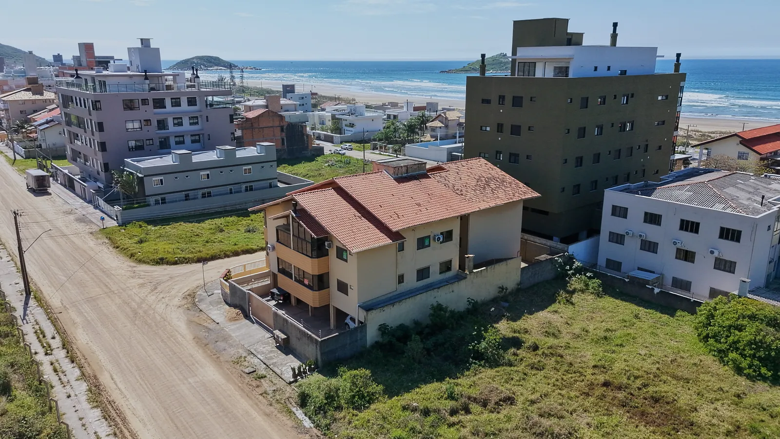 Vista aérea do prédio de esquina, com a praia e o mar ao fundo.